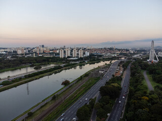 Fototapeta premium Rising sun on a river within the metropolis of São Paulo with the Pinheiros riverside.