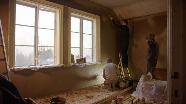 Multicultural friends renovate an old house using sustainable clay plaster mix