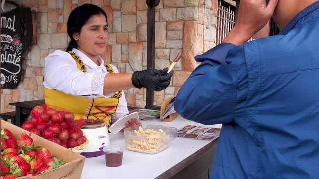 Waitress dressed in typical German clothes offers customers strawberries and chocolates to try at the fair, Colonia Tovar Venezuela