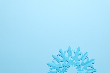 One beautiful paper snowflake on light blue background, top view. Space for text