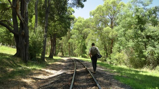 A hobo walks a historic railway line with his bedroll.