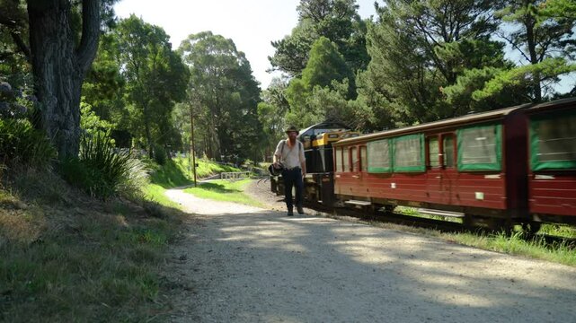 A traveling hobo walks past a historic steam engine train while walking a railway line in Australia.