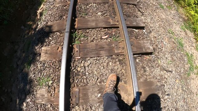 Point of view shot of a hobo man walking along a historic railway line in Australia.