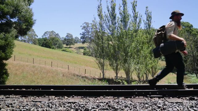 Slow motion shot of a traveling hobo swagman walking a railway line in Australia.
