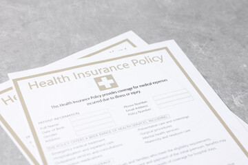Health insurance policy forms on grey table, closeup