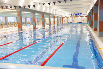 Obraz premium People swimming in indoor pool with clean water and lane dividers