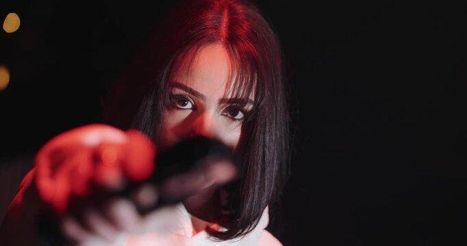young beautiful woman aiming with gun at night