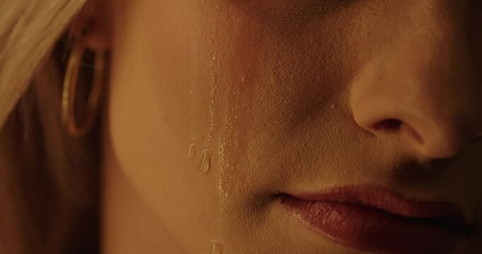 A tear flows down the cheek of a beautiful woman in slow motion, without eyes