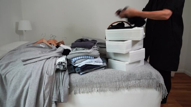 Woman sorting through bins of clothing to declutter and organize in bedroom
