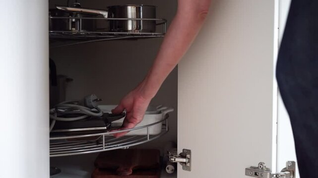 Kitchen corner cabinet with lazy Susan being swung around by woman