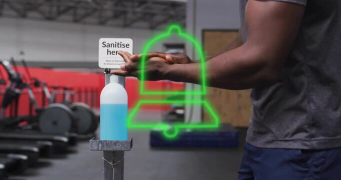 Person sanitizing hands with green bell animation over gym equipment in background
