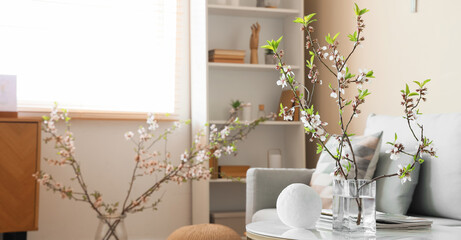 Beautiful living room with sofa and coffee table with vase of blooming branches