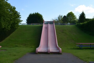Twin Pink Slides at Park Playground on Grassy Hill