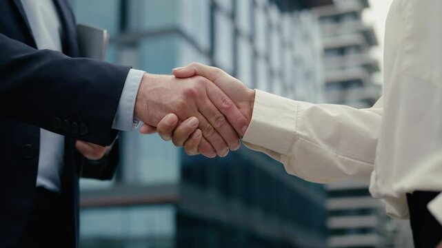 Close up business handshake two unrecognizable multiracial diversity people in city handshaking hands gestures talking African American businesswoman woman female Caucasian man businessman male deal