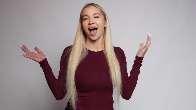 See this cute blonde girl expressing excitement, raising her hands, shouting "Aaa!", winking, and smiling on a white background.
