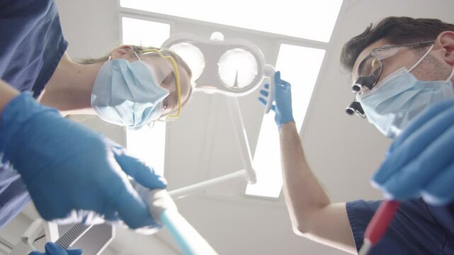 Dental patient upward POV of dentist and assistant with masks doing oral checkup