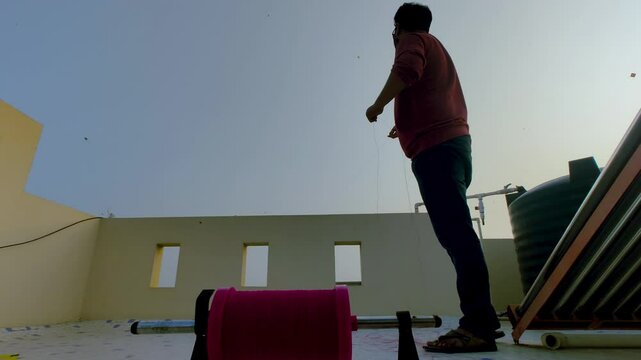 4K footage of man flying kite on rooftop during festival, with clear blue sky and warm light. joy, tradition and cultural celebration of kite flying events.