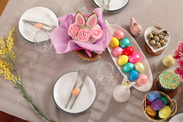 Festive table setting with flowers, Easter cakes and painted eggs