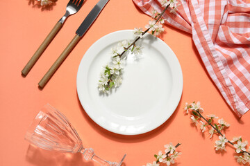 Beautiful table setting with blossoming branches on orange background