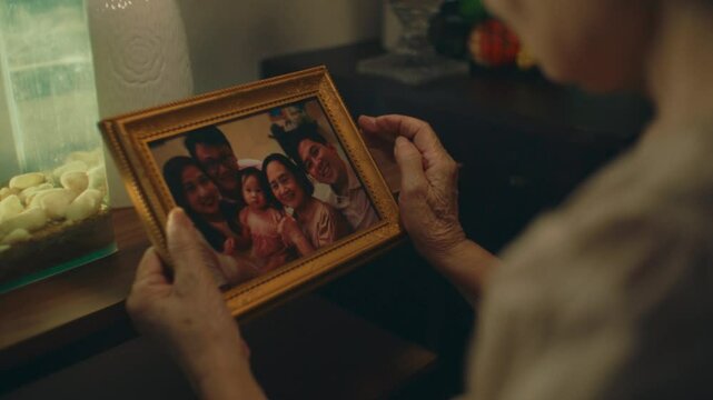 Elderly woman holding a family photo, reminiscing with nostalgia and longing