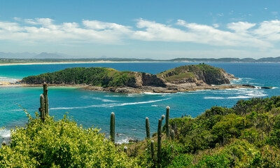 Fototapeta premium Conchas Beach. With lots of vegetation, mountains and rocks around. Sea with crystal clear waters and beautiful blue sky. Cabo Frio, Rio de Janeiro, Brazil.