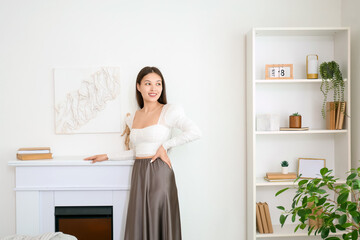 Young Asian woman with 3D painting on light wall above fireplace at home