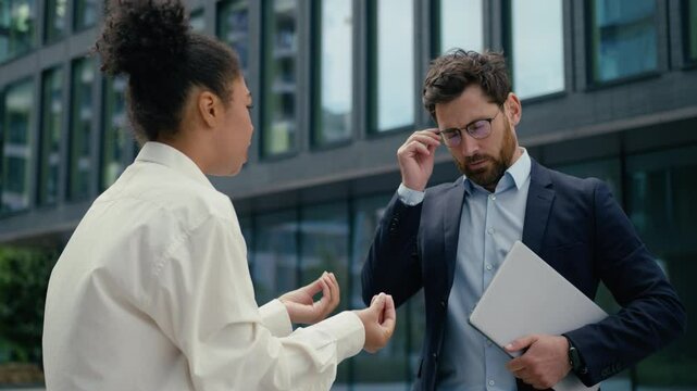 African American aggressive authority angry boss leader businesswoman woman female scolding talking to Caucasian man businessman male worker bad work two multiracial business people in city conflict