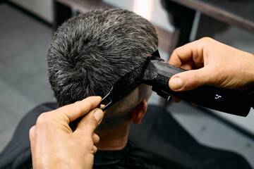 A hairdresser is expertly cutting the hair of a client using clippers in a contemporary barbershop. The atmosphere is stylish and focused on providing quality grooming services