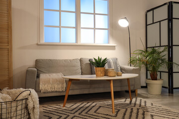 Interior of stylish living room with comfortable sofa, coffee table and glowing lamps