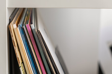 Colorful vinyl record sleeves in a white shelf closeup