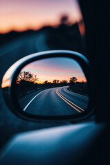 Serene Sunset Reflection on a Winding Road Captured in Car Side Mirror