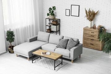 Stylish interior of living room with comfortable sofa, coffee table and houseplant