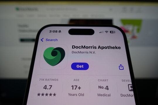 Kiel, SH, Germany March 27 2025: DocMorris Apotheke app appears in App Store on smartphone ready for download, with company website visible in the background