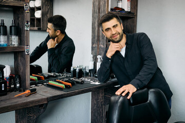 A skilled hairdresser stands beside a grooming station, smiling while leaning on a chair