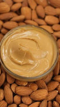 Almond butter scooping with golden spoon, close up. Creamy smooth almond butter and whole almonds without shell