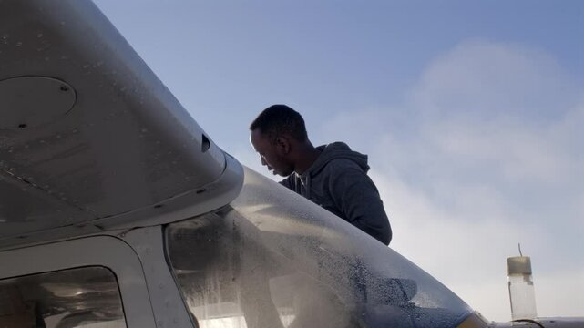 Male Black Pilot Checks Fuel Level in the Wing of an Airplane SLOMO