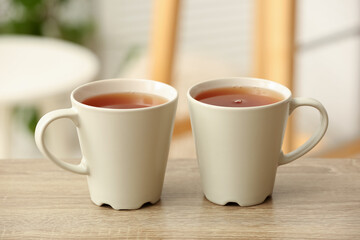 Cups of hot tea on wooden table on blurred background. Closeup