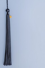 Elegant tassel hanging against soft blue background, showcasing