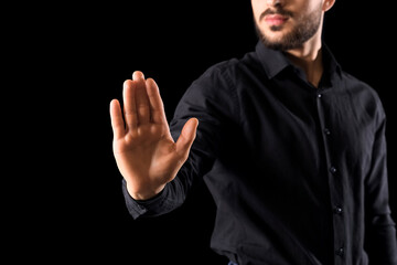 Businessman showing stop gesture on black background, closeup. Goal concept