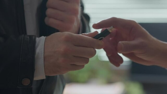 Hand discreetly pulling a USB stick from a jacket pocket and handing it to another person. Data transfer, hacking, confidential exchanges. cybersecurity, corporate leaks, intelligence operations.