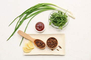 Wooden bowl with fried insects, arugula, green onion and slices of lemon on white background