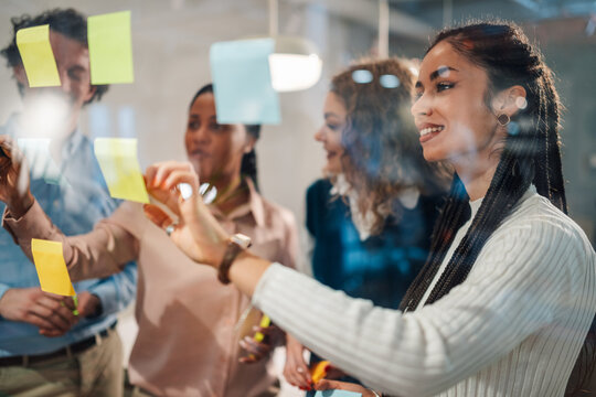 Business team brainstorming and planning using sticky notes on glass wall