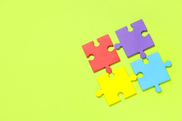 Colorful puzzle pieces on green background. Autistic disorder concept