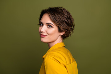 Fototapeta premium Confident young woman with short brunette hair smiling on a khaki background wearing a stylish yellow shirt