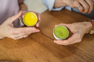 Close up on female hands hold colorful natural creams for body