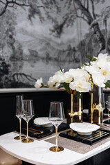 An elegant dining setup with candles, crystal glasses, and a lush floral centerpiece, creating a warm, inviting ambiance for a memorable evening gathering. Table setting in modern restaurant. Vertical