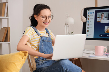 Teenage girl with laptop working online at home