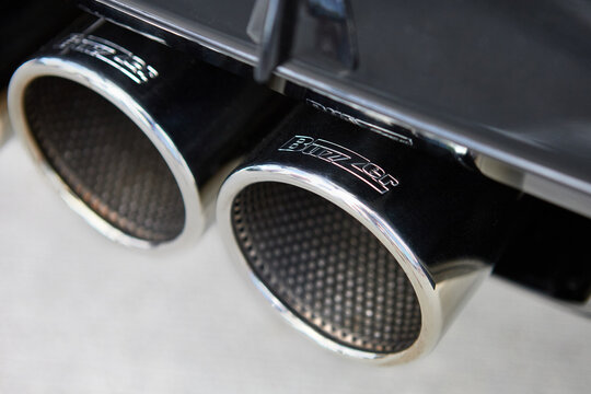 Paris, France, August 20, 2022: Buzzle stainless steel exhaust muffler pipe tip of sports car close up. Dual exhaust.