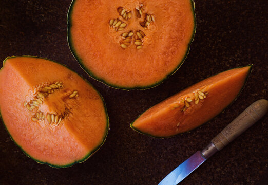 Melona naranja cortada sobre una superficie oscura