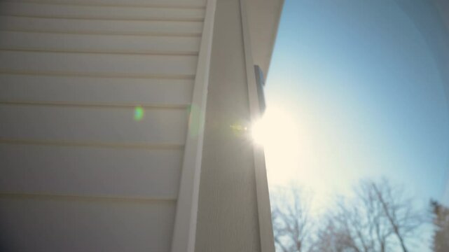 The view of White siding house wall with modern panels at sunny day, providing a sleek and classic exterior look. move camera view